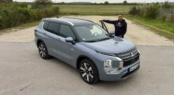 Mann lehnt am neuen Mitsubishi Outlander. Keine Probleme hier, nur ein schöner SUV.