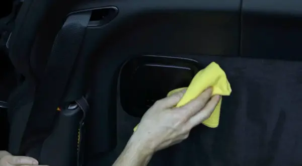 Hand poliert matten Kunststoff im Auto mit gelbem Tuch.