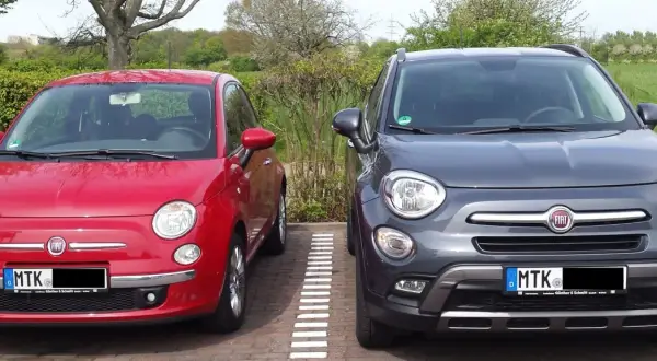 Zwei Fiat 500X, rot und grau, parken nebeneinander. Der graue hat ein paar kleine Probleme, die man auf den ersten Blick nicht sieht.