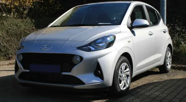 Silberner Hyundai i10, der auf einem gepflasterten Weg steht. Ein Blick auf die Frontpartie, die typische Hyundai i10 Krankheiten wie Rost an den Radläufen oder Probleme mit dem Getriebe vermeiden sollte.