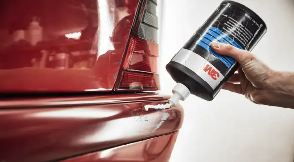 Hand trägt Politur auf roten Kotflügel auf, um klavierlack auto reinigen.