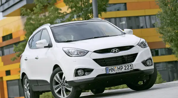 Weißer Hyundai ix35 vor moderner Architektur. Mögliche Hyundai ix35 Probleme werden hier nicht gezeigt.