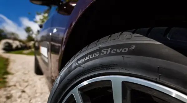Nahaufnahme eines Hankook Ventus S1 evo 3 Reifens auf einem dunklen Auto, bereit für einen Test auf einer Schotterstraße.