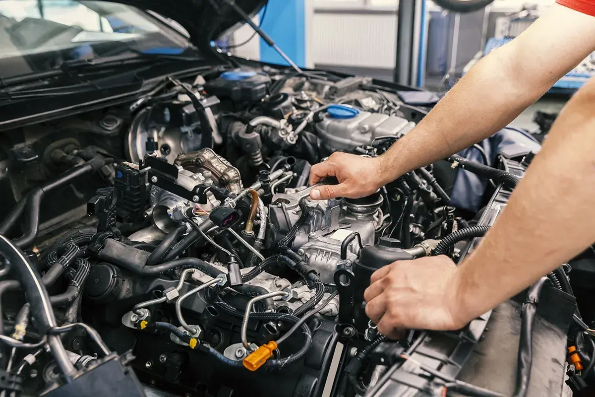 Mechaniker arbeitet am Motor eines Autos. Informieren Sie sich über die motorraum reinigen kosten, um Ihr Fahrzeug in Topform zu halten.