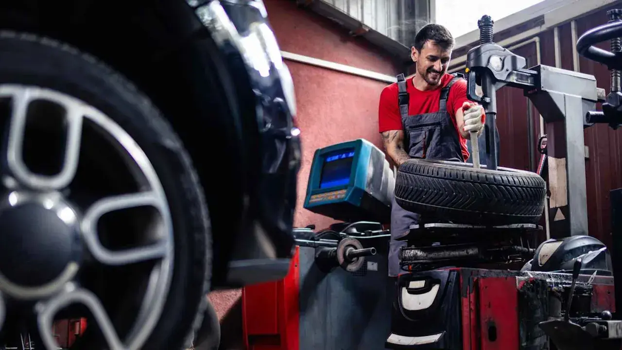 Mechaniker wechselt Reifen an einem BMW. Informieren Sie sich über die BMW Reifenwechsel Kosten.