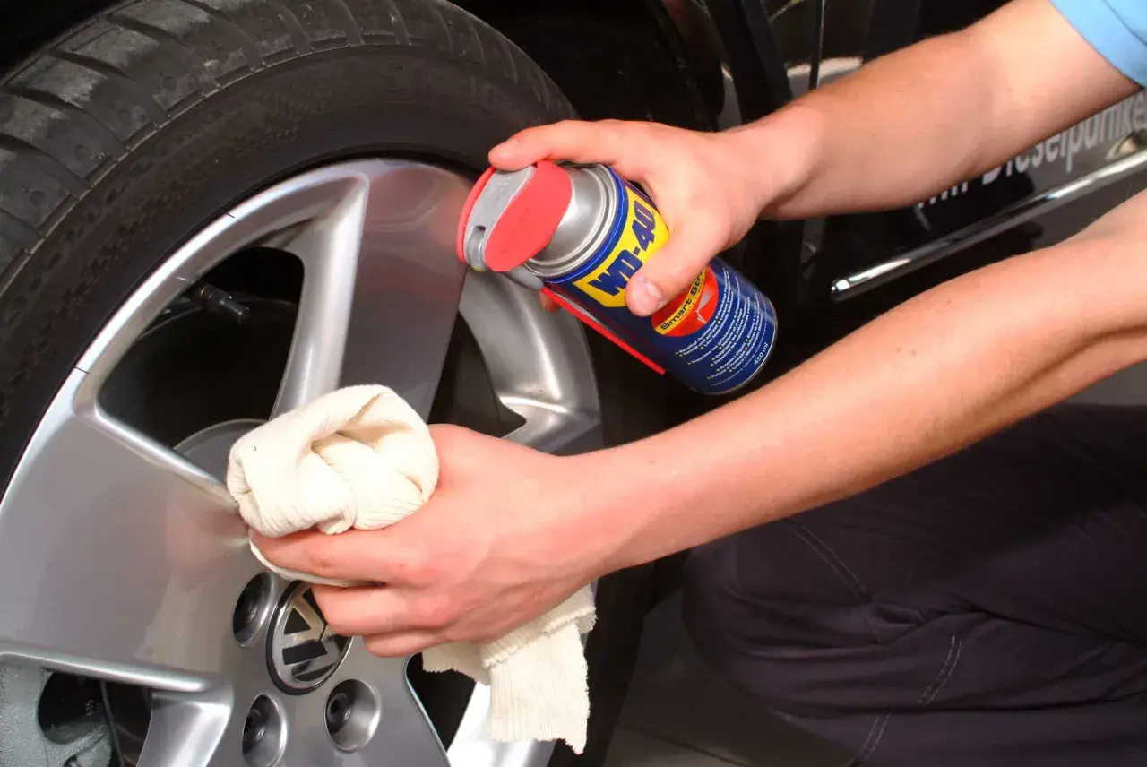 Hände reinigen Felgen mit einem Tuch und WD-40.