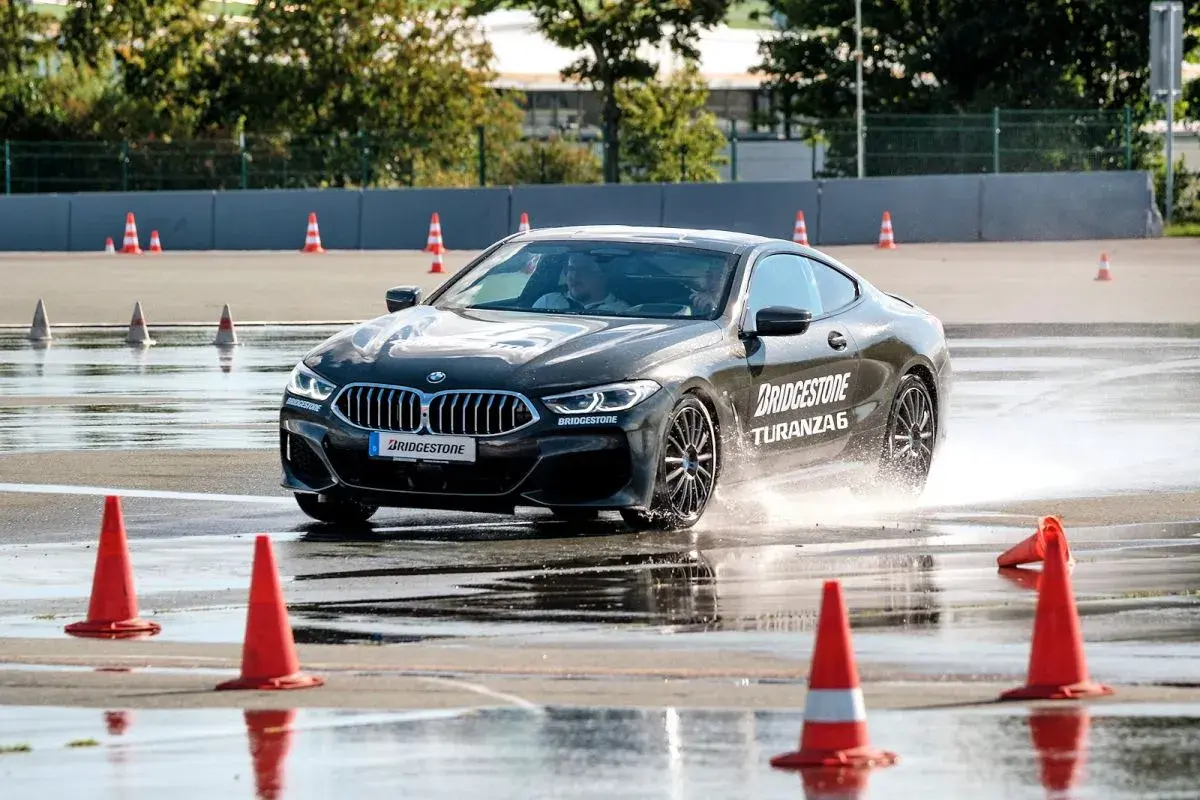 BMW fährt auf nasser Strecke, Wasser spritzt. Bridgestone Turanza 6 Test auf dem Prüfstand.