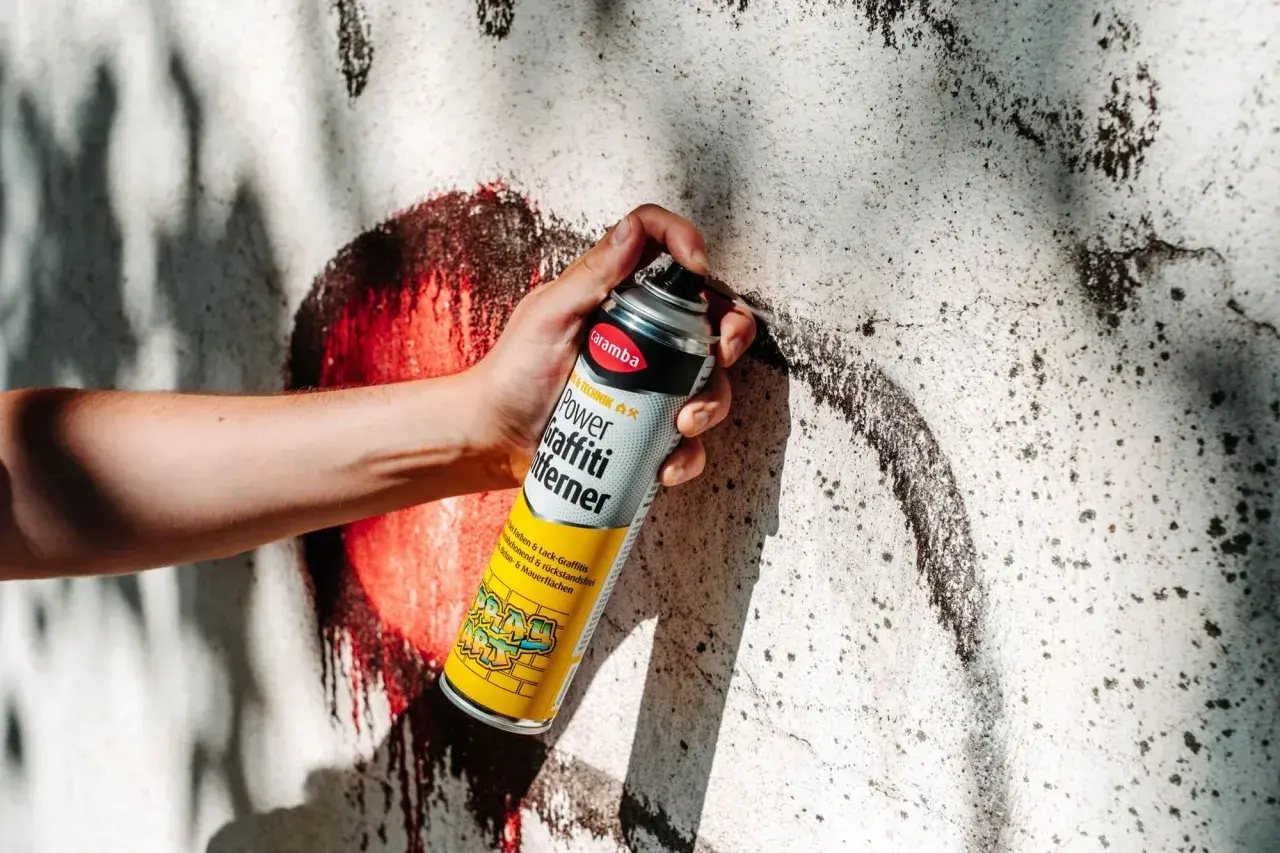 Hand hält Sprühdose mit Graffiti-Entferner. Ideal, um Graffiti von Wänden zu entfernen, fast wie felgenreiniger selber machen.
