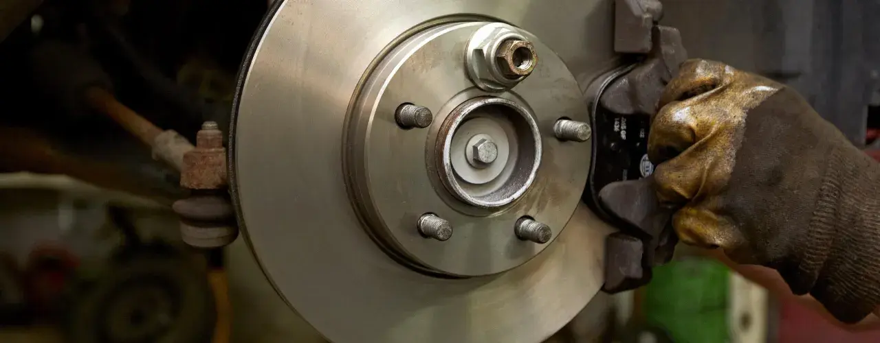 Hand in glove works on a car brake disc, ready to replace the bremsbelag.