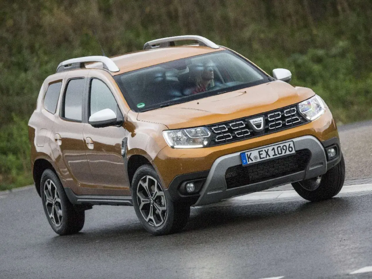 Ein oranger Dacia Duster fährt auf nasser Straße. Mögliche Dacia Duster Probleme sind hier nicht sichtbar.