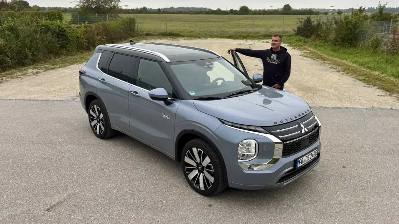 Mann lehnt am neuen Mitsubishi Outlander. Keine Probleme hier, nur ein schöner SUV.