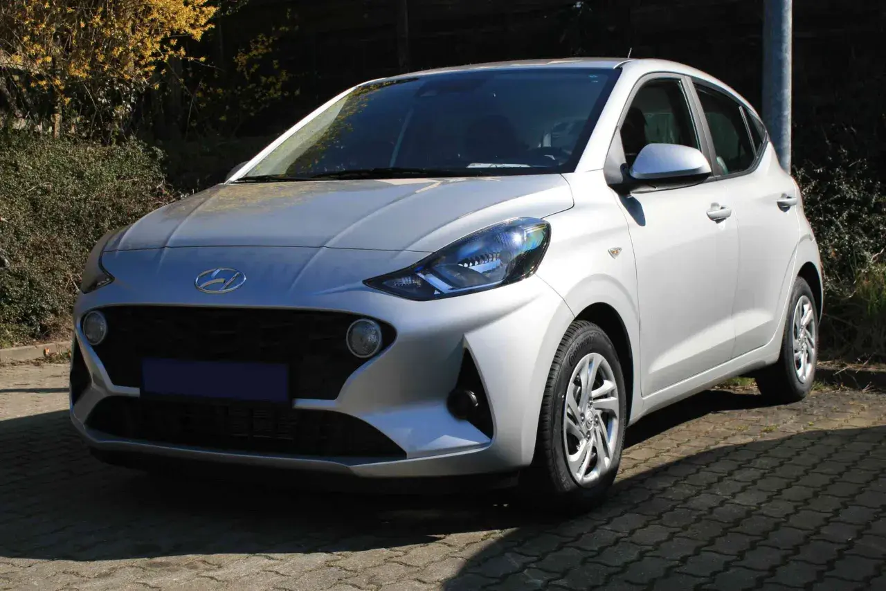 Silberner Hyundai i10, der auf einem gepflasterten Weg steht. Ein Blick auf die Frontpartie, die typische Hyundai i10 Krankheiten wie Rost an den Radläufen oder Probleme mit dem Getriebe vermeiden sollte.