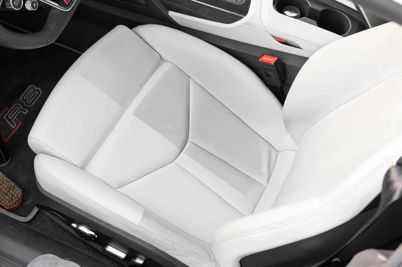 Helles Leder reinigen im Audi R8. Der Sitz zeigt leichte Verschmutzungen, die mit einem Bürstchen und Reinigungsmittel entfernt werden.