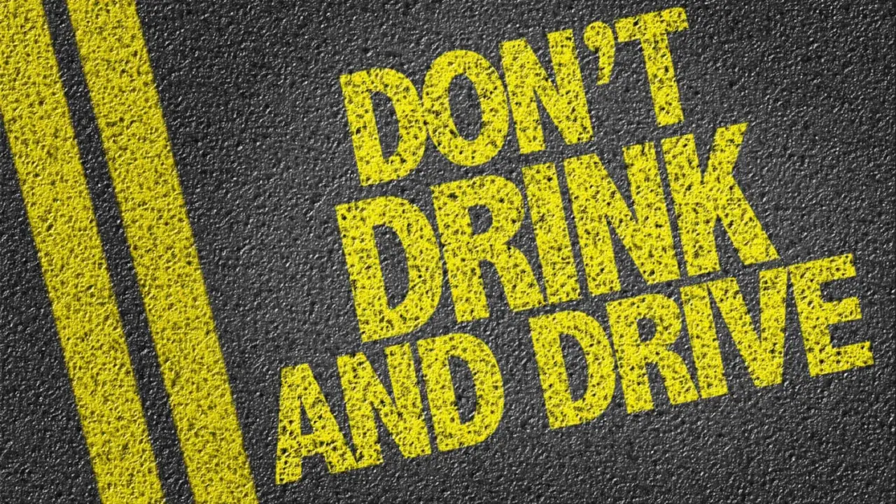 Gelbe Schrift auf Asphalt: "DON'T DRINK AND DRIVE". Informiert über die Promillegrenze Italien.