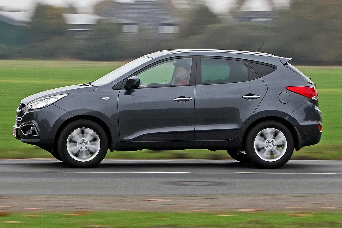 Grauer Hyundai ix35 f&auml;hrt auf einer Stra&szlig;e. Ein Fahrer ist im Auto zu sehen. M&ouml;gliche Hyundai ix35 Probleme werden diskutiert.