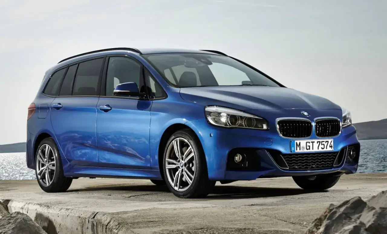 Blauer BMW 218i Active Tourer am Wasser, der trotz seiner Eleganz auch Probleme haben kann.