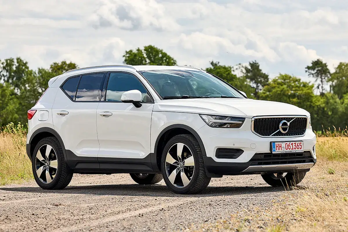 Wei&szlig;er Volvo XC40 auf Schotterweg, umgeben von B&auml;umen und Feldern. Ein Blick auf das Fahrzeug, das trotz m&ouml;glicher Volvo XC40 Probleme eine gute Figur macht.