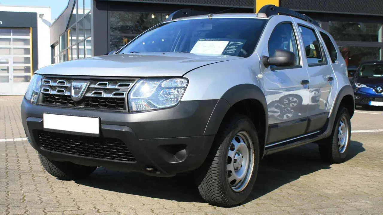 Silberner Dacia Duster vor einem Autohaus. Ein Zettel auf der Windschutzscheibe deutet auf m&ouml;gliche Dacia Duster Probleme oder Angebote hin.