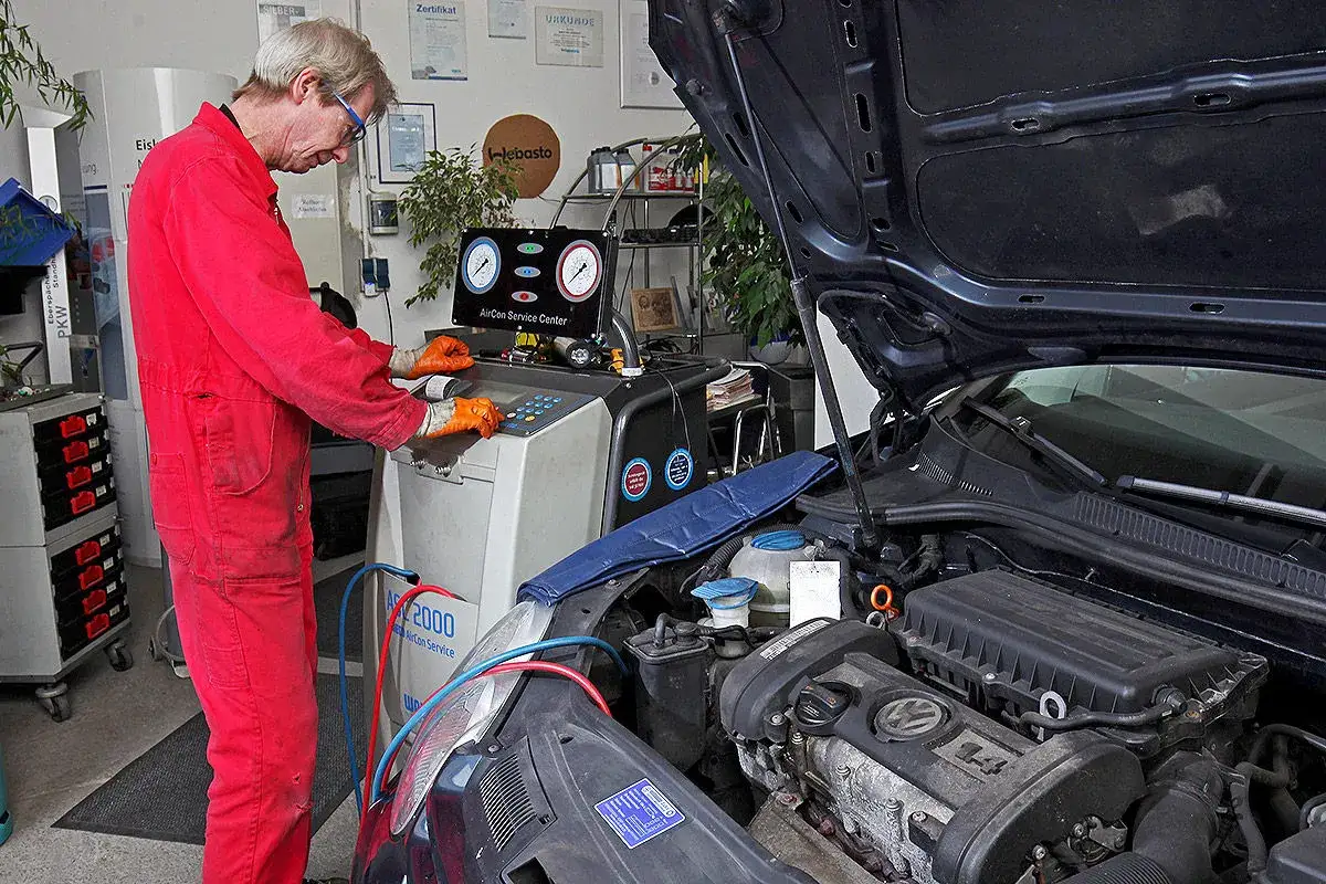 Mechaniker pr&uuml;ft Klimaanlage. Die Kosten f&uuml;r die Klimaanlage reparieren sind hier im Blick.
