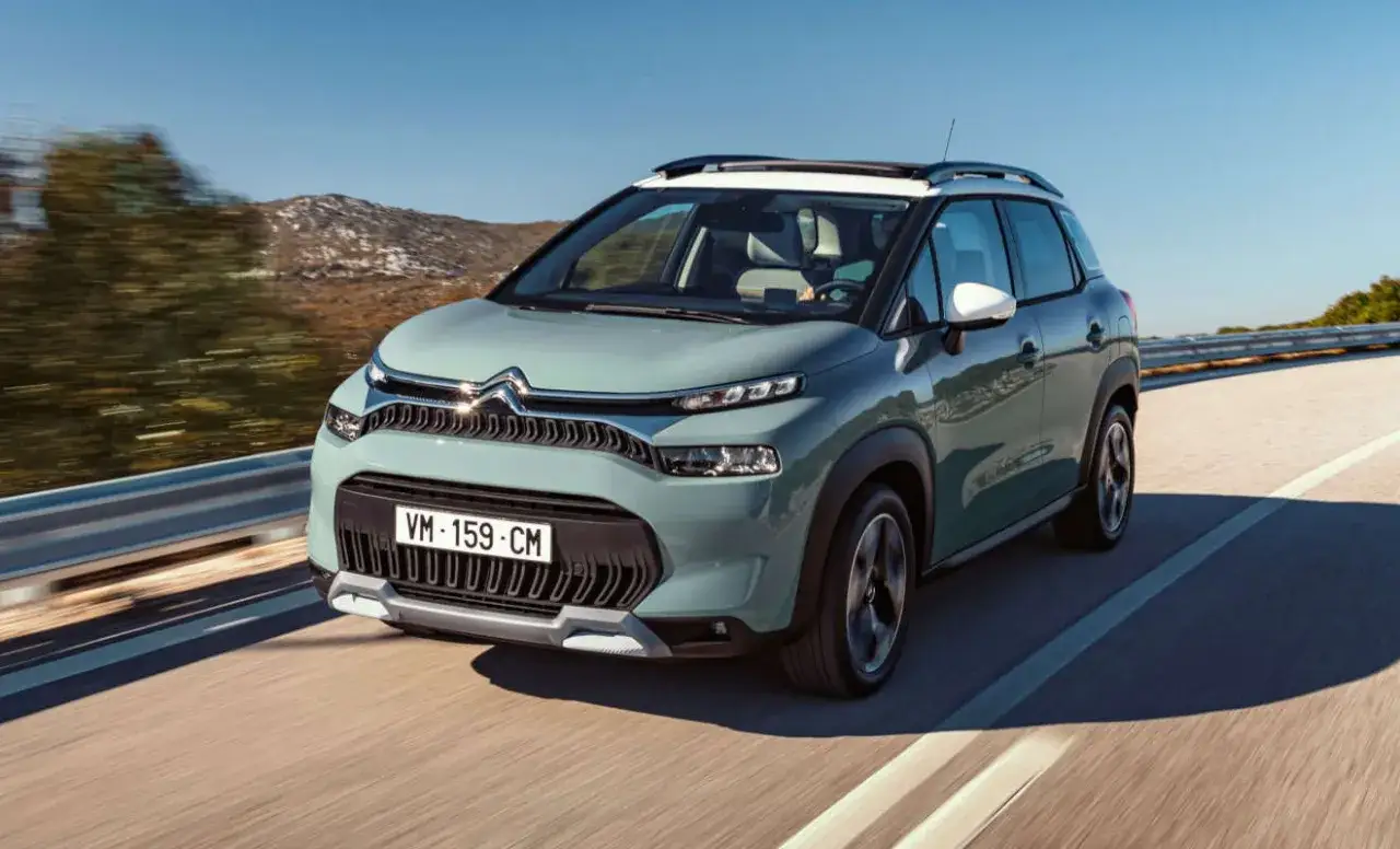 Ein mintgr&uuml;ner Citro&euml;n C3 Aircross f&auml;hrt auf einer sonnigen Stra&szlig;e. Trotz seines schicken Designs gibt es Berichte &uuml;ber Citro&euml;n C3 Aircross Probleme.