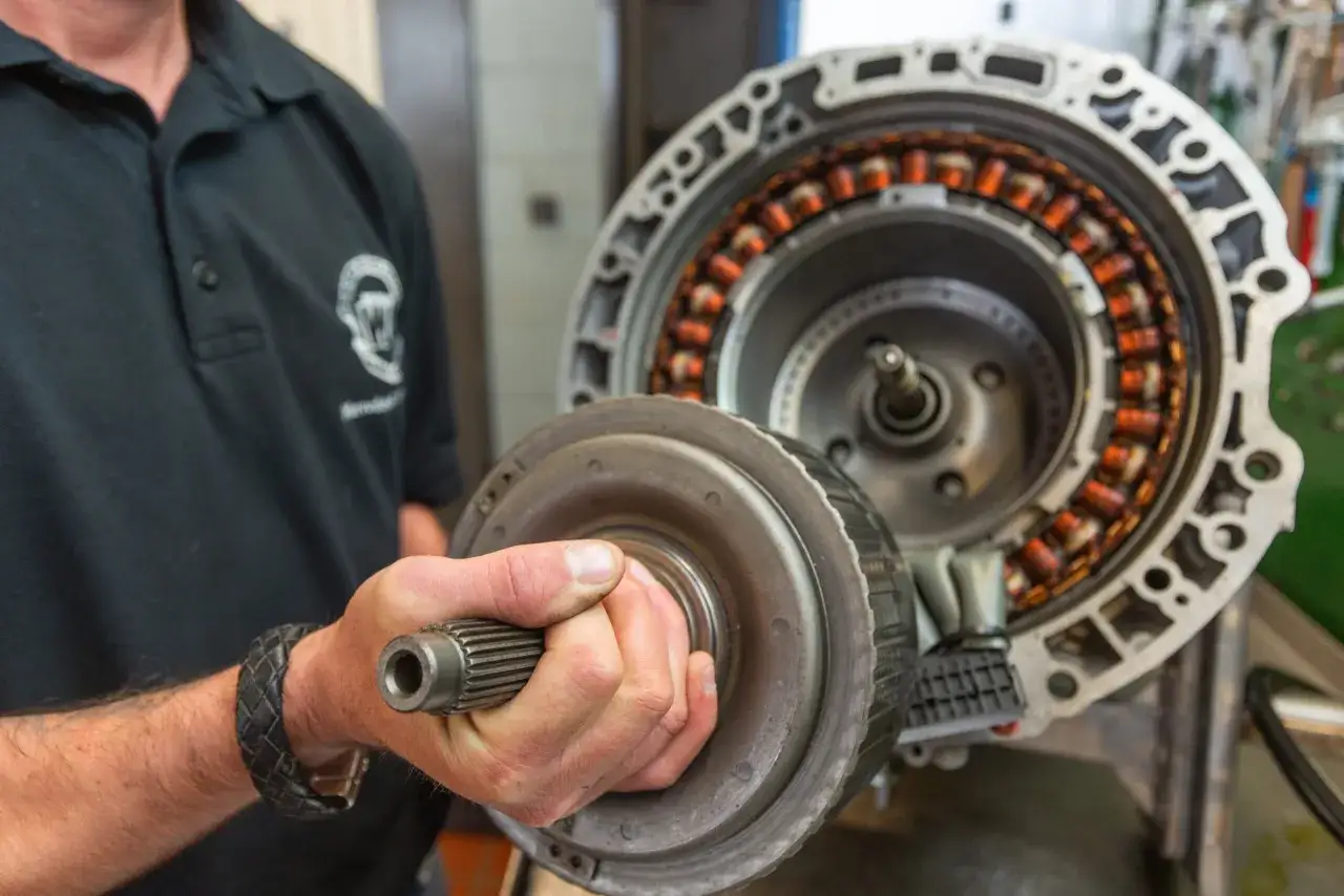 Mechaniker h&auml;lt Drehmomentwandler vor offenem Getriebe. Informieren Sie sich &uuml;ber die getriebe wechseln kosten.