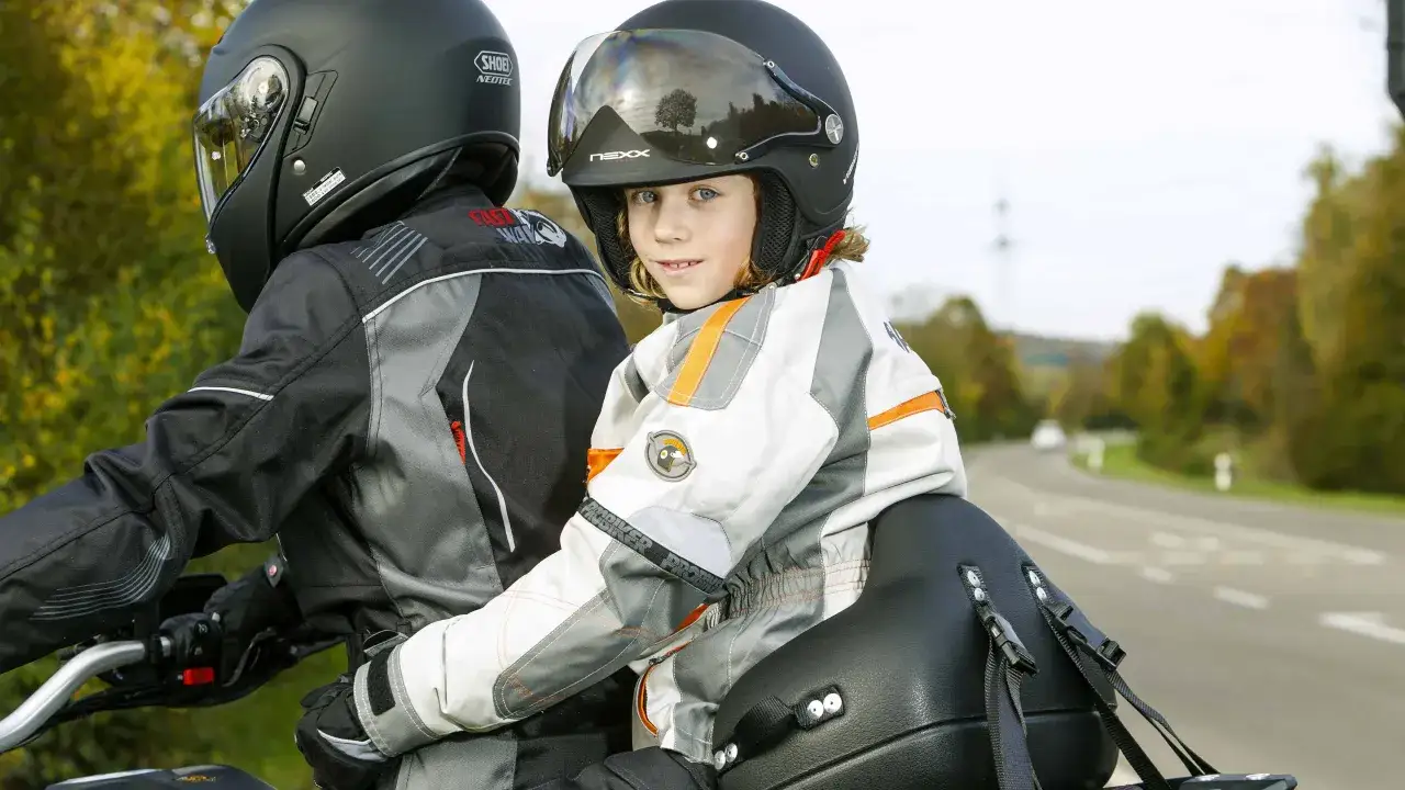 Ein Kind mit Helm f&auml;hrt sicher auf einem Motorrad mit.