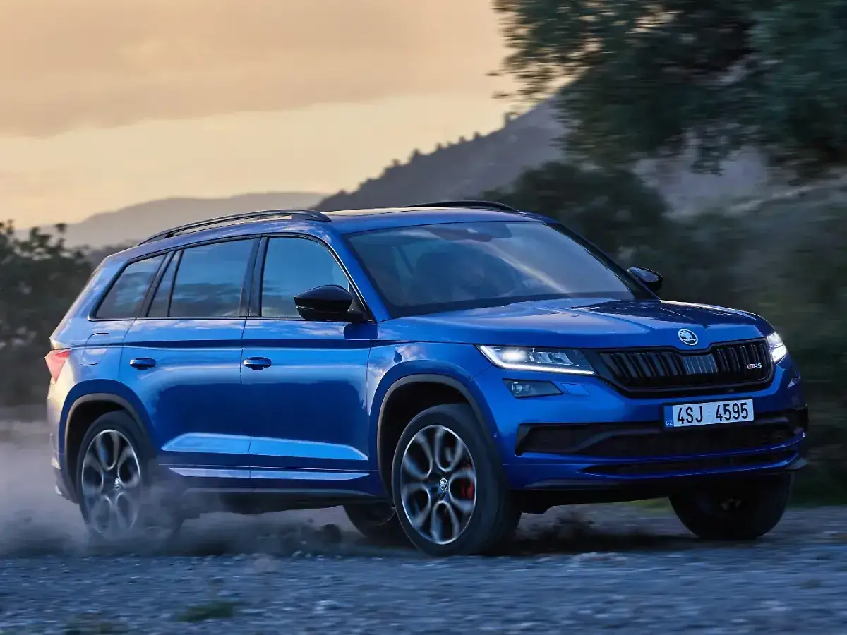 Blauer Skoda Kodiaq f&auml;hrt auf Schotterweg, Staub aufwirbelnd. Trotz seiner Robustheit gibt es Berichte &uuml;ber Skoda Kodiaq Probleme.