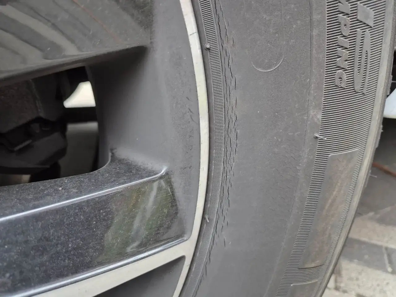 Nahaufnahme eines Autoreifens mit einem deutlichen riss im reifen seitlich. Die Felge ist ebenfalls sichtbar.