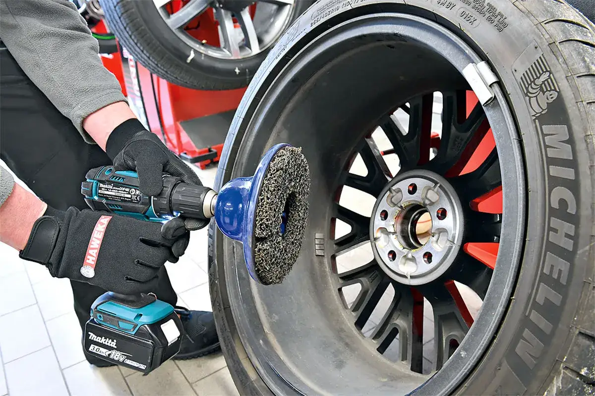 Mechaniker reinigt Felge mit Schleifaufsatz. Guter Preis f&uuml;r Reifen auswuchten und Felgenpflege.