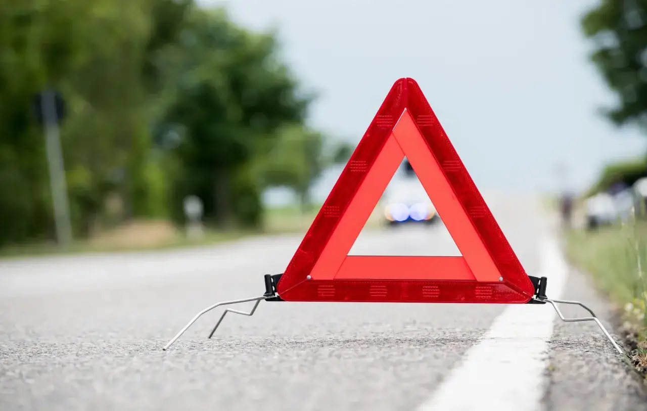 Warnblinker leuchten hinter einem Warndreieck. Ein Unfall, der zu Fahrerflucht in der Probezeit führen könnte, ist hier sichtbar.