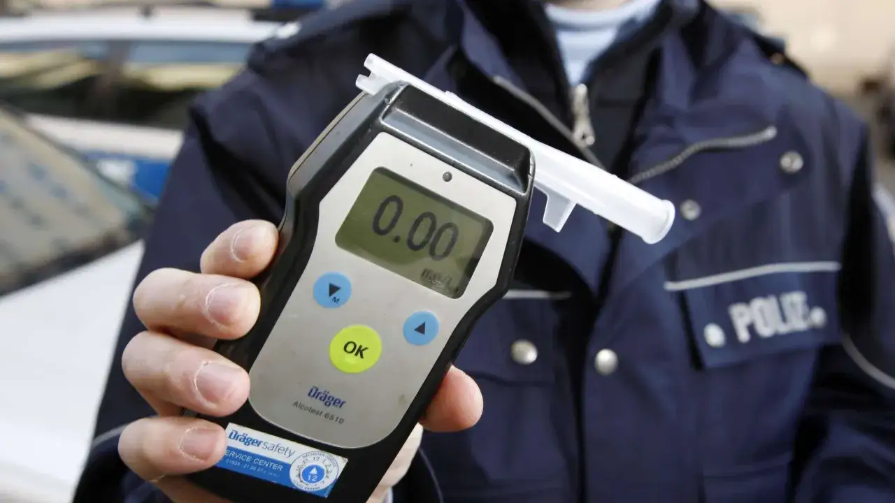 Polizist h&auml;lt Atemalkoholtestger&auml;t. Null Promille. Kein Alkohol am Steuer, auch nicht in Spanien.