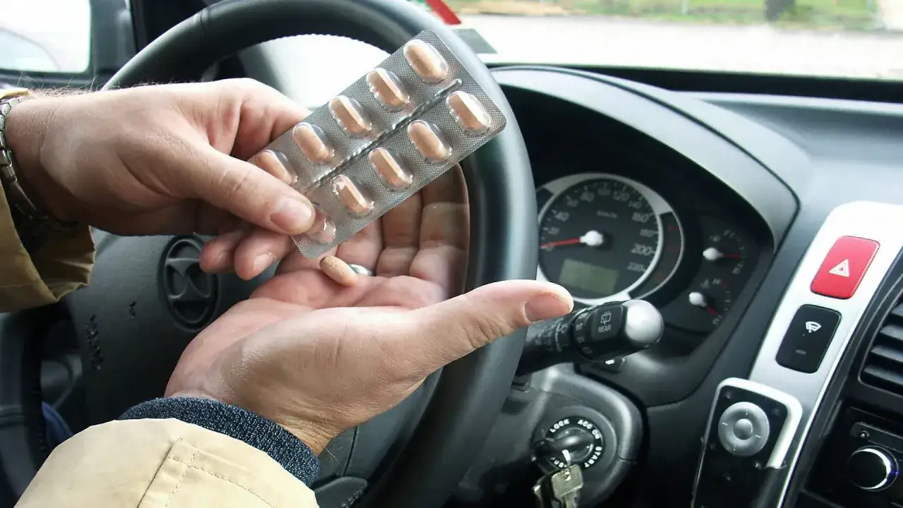 Mann h&auml;lt Ibuprofen-Blister und eine Pille in der Hand, bereit zum Autofahren. Vorsicht bei Medikamenten und Verkehr!