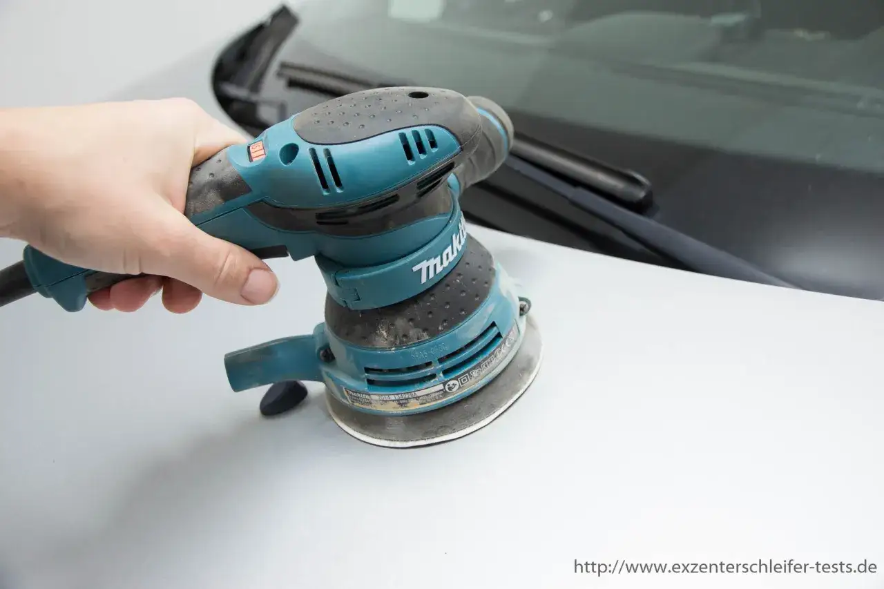 Hand h&auml;lt einen Exzenterschleifer, bereit zum polieren des Autos.