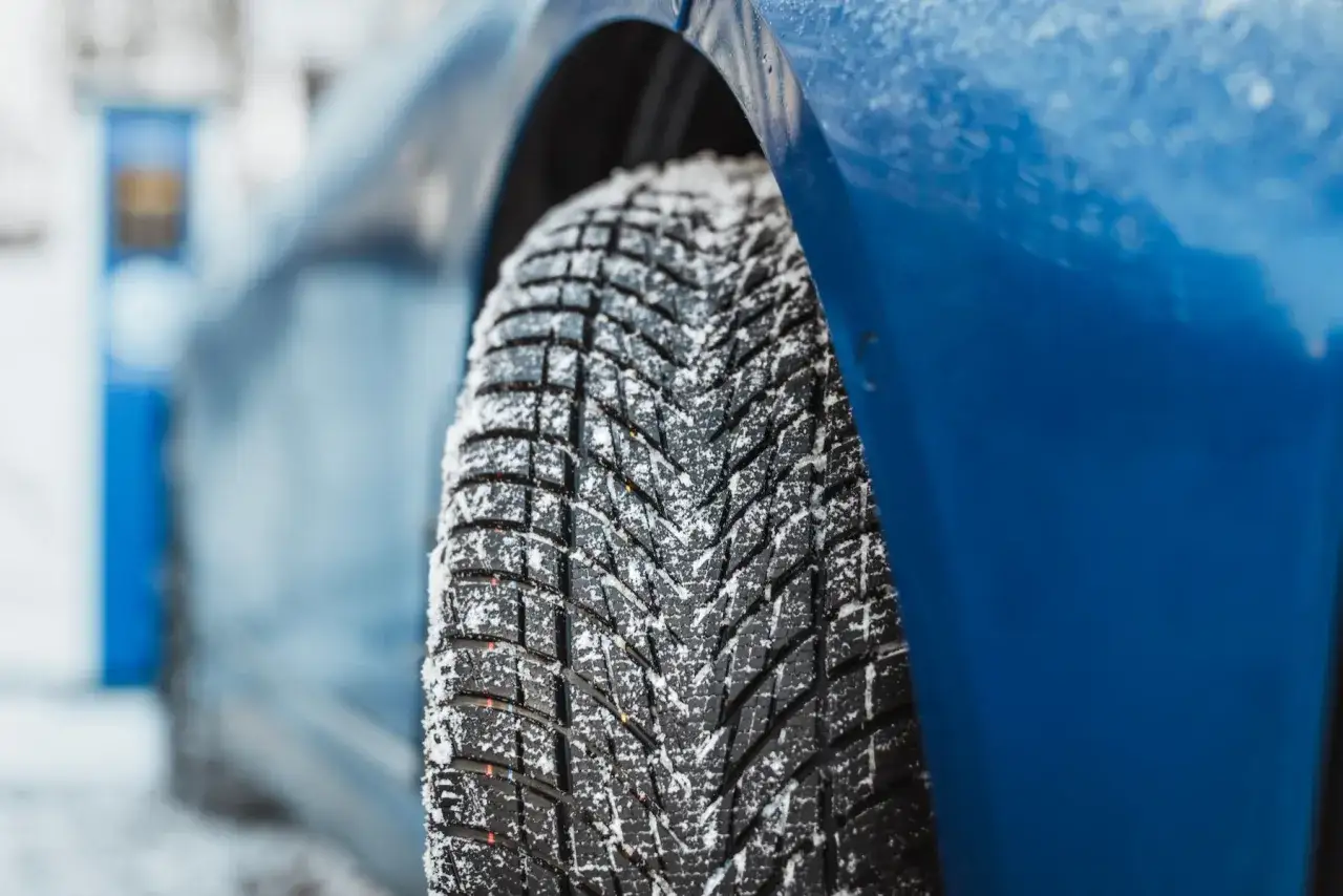 Nahaufnahme eines blauen Autos mit Schnee auf dem Reifen. Der Reifen ist ein Goodyear UltraGrip Performance 3, bereit f&uuml;r den Test.