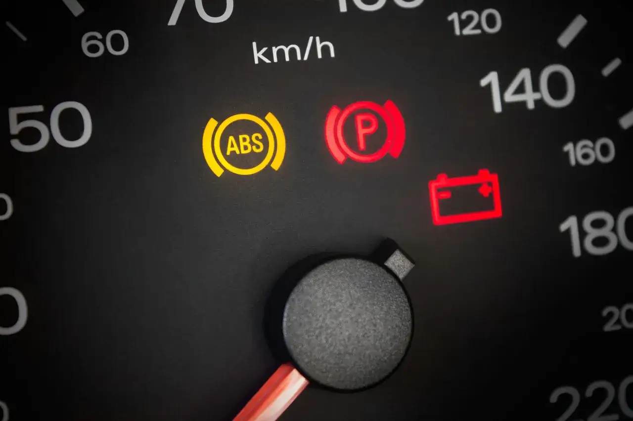 Armaturenbrett mit leuchtenden Warnleuchten: ABS, Handbremse und Batterie. ABS-Leuchte deutet auf einen defekten ABS-Sensor hin.
