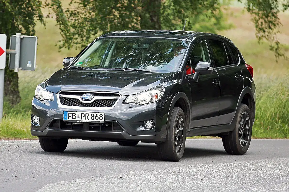 Dunkelgrauer Subaru XV auf asphaltierter Stra&szlig;e, umgeben von Gr&uuml;n. Ein Blick, der Fragen zu m&ouml;glichen Subaru XV Problemen aufwirft.