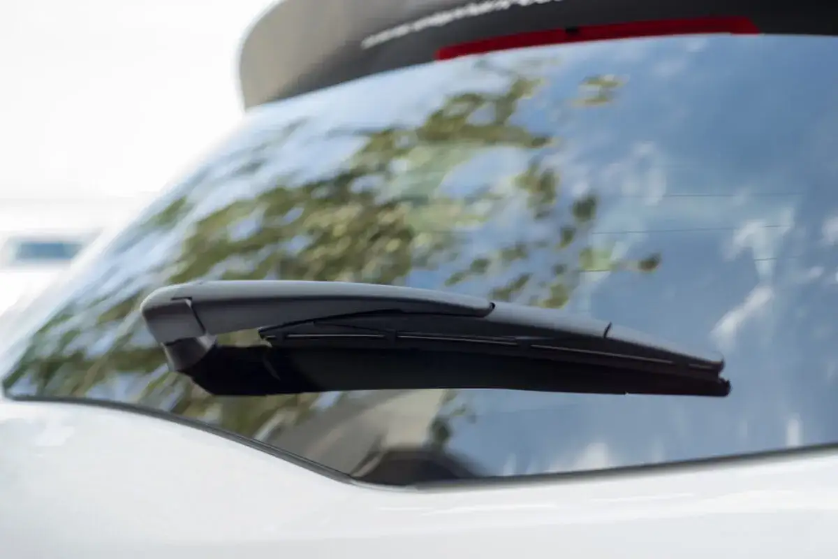 Nahaufnahme eines Heckscheibenwischers, bereit zum Wechseln. Der Wischerarm ist schwarz und liegt auf der Heckscheibe eines wei&szlig;en Autos.