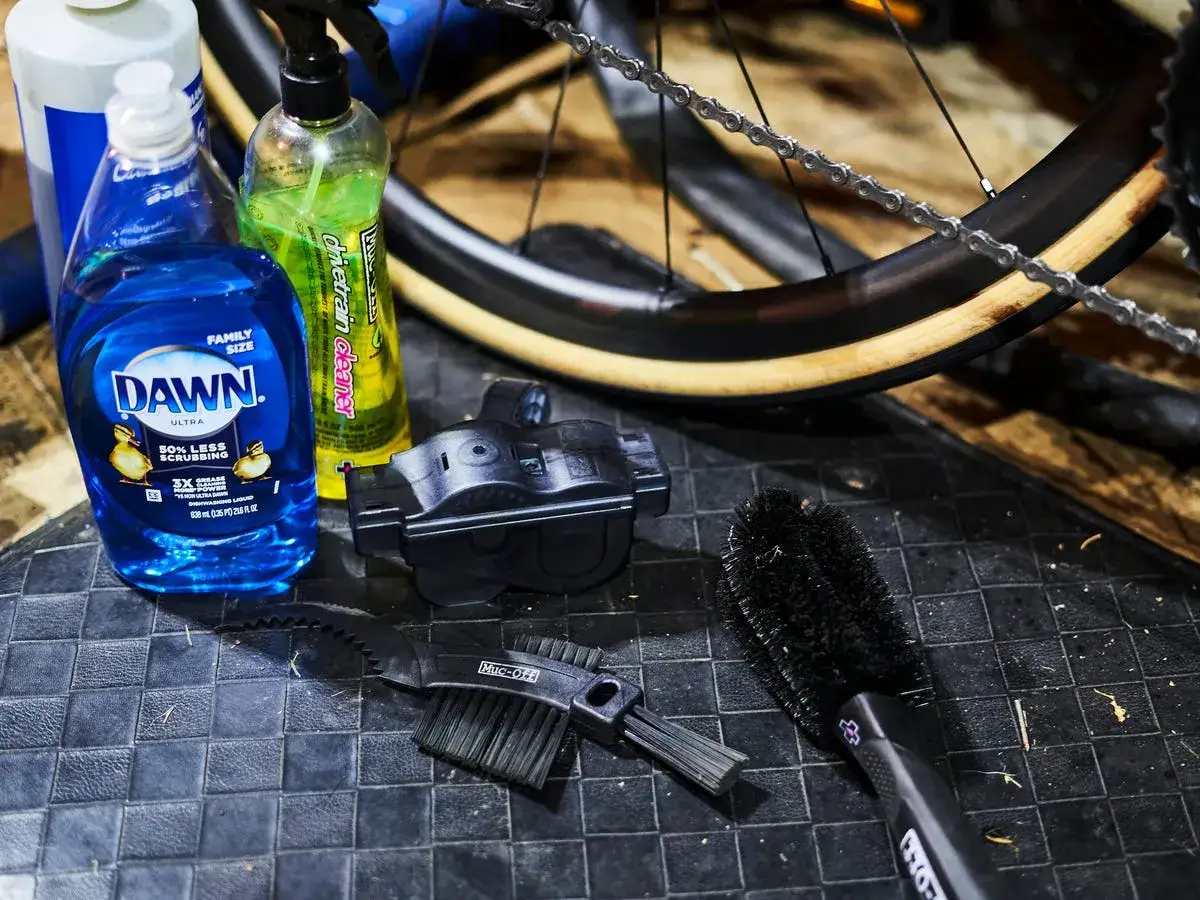 Hausmittel zur Fahrradkette reinigen: Sp&uuml;lmittel, Kettenreiniger und B&uuml;rsten liegen bereit.