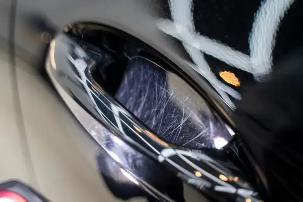 Detailaufnahme eines zerkratzten Autolacks, der auf eine Politur wartet. Der **Lackschaden** zeigt feine Kratzer, die durch das Polieren behoben werden können.