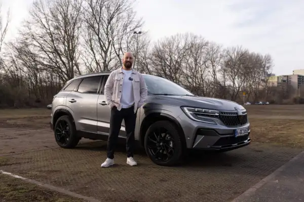 Mann steht neben grauem Renault Austral. Keine Probleme mit diesem Auto, nur ein toller Tag.
