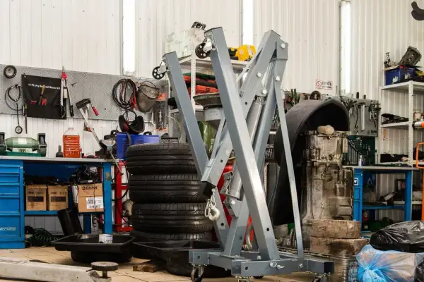 Geräte und Reifen in einer **freien Werkstatt**. Ein Motor hängt an einem Kran, Werkzeuge sind an der Wand befestigt.
