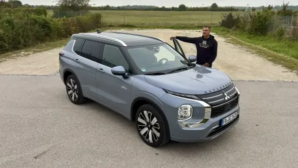 Mann lehnt am neuen Mitsubishi Outlander. Keine Probleme hier, nur ein schöner SUV.