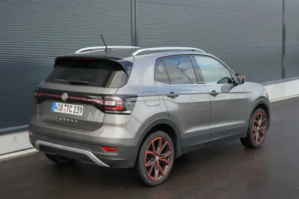 Grauer VW T-Cross mit auffälligen roten Felgen. Hoffentlich gibt es keine vw t-cross probleme, die diese schönen Räder beeinträchtigen.