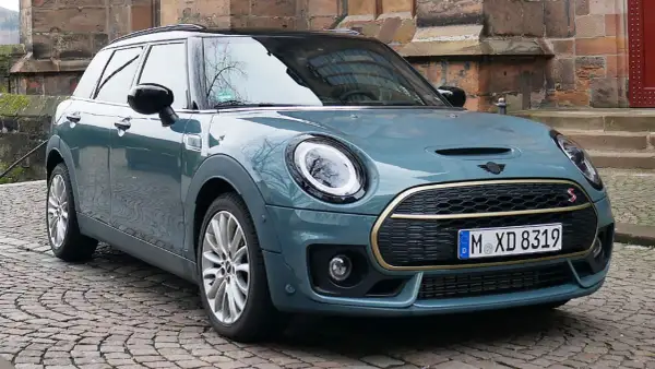 Mini Clubman in Petrolblau Metallic vor historischer Kulisse. Bekannte Mini Clubman Schwachstellen sind hier nicht sichtbar.